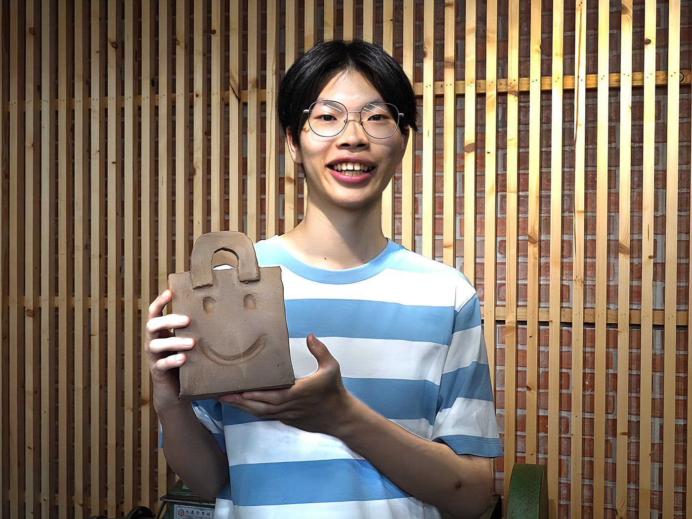 華梵大學智慧生活設計學系學生李翊愷戒除手機成癮，開心展示陶藝作品。  